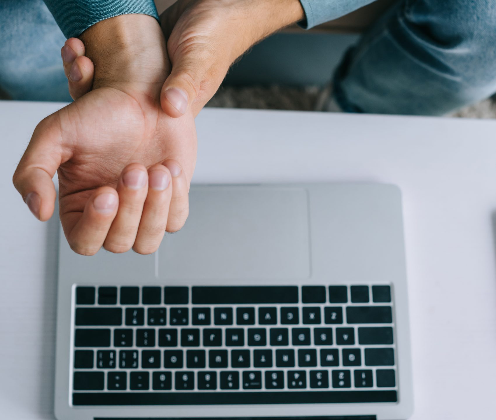 cropped shot of man having wrist pain while using laptop